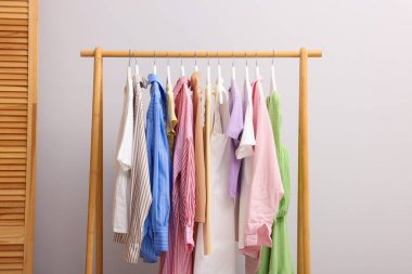 İçerideki duvarın yanındaki askıda asılı farklı şık kıyafetler.