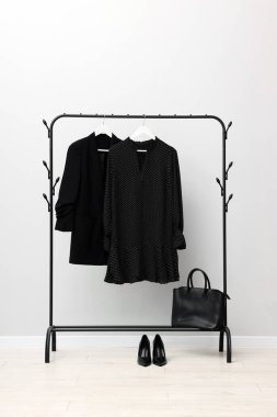 İçerideki duvarın yanında asılı farklı şık kıyafetler, çanta ve ayakkabılar.