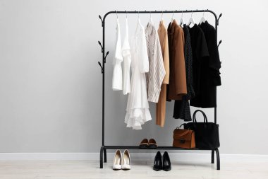 Askıda asılı farklı şık kıyafetler, açık duvarın yanında çantalar ve ayakkabılar, metin için yer