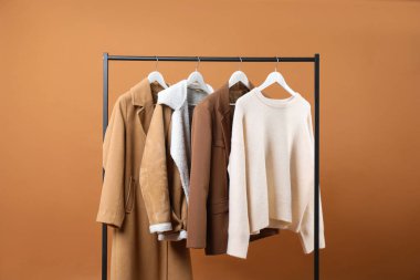 Kahverengi arka planda askıda asılı farklı elbiseler