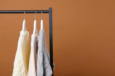 Esmer arka planda askıda asılı farklı kıyafetler, yakın plan. Metin için boşluk