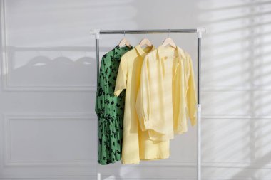 Beyaz duvarın yanındaki askıda asılı farklı şık kıyafetler.