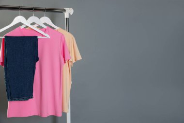 Gri arkaplanda asılı duran farklı şık kıyafetler, metin için boşluk