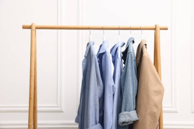 Beyaz duvarın yanında asılı duran farklı kadın kıyafetleri.