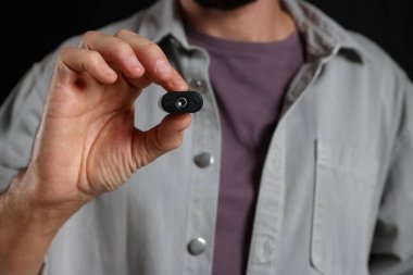 Siyah arka planda gizli casus kamerası olan adam, yakın plan.