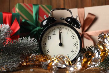 Alarm saati, süs, köknar ağacı dalları ve ahşap masada hediye kutuları, yakın plan. Yeni yıl tebrik kartı.