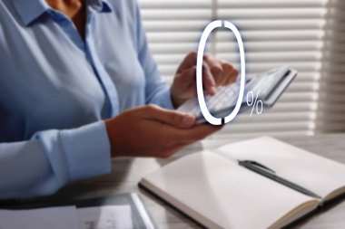 Masada hesap makinesi kullanan bir kadın, yakın plan. Yüzde 0 sıfır komisyonu temsil ediyor