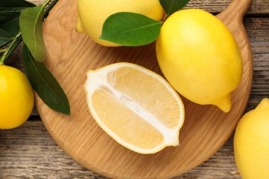 Tahta masanın üzerinde yeşil yapraklı limonlar var.