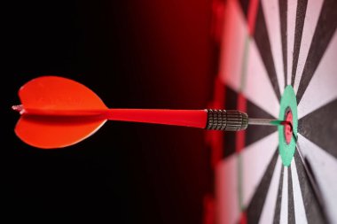 Koyu kırmızı arka planda dart tahtası, yakın plan.