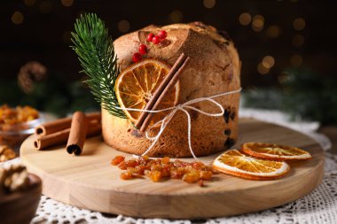 Noel yemeği. Lezzetli Panettone pastası, malzemeler ve arka planda arka planda bulanık ışıklı şenlikli dekor, yakın plan. Bokeh etkisi