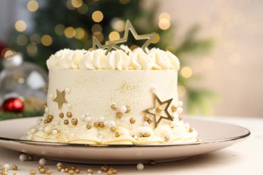 Bulanık ışıklara karşı beyaz masanın üzerinde Noel süsü olan enfes bir pasta.