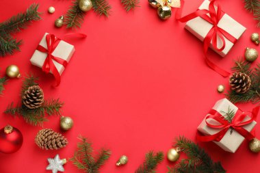 Kırmızı arka planda dekoru ve Noel hediyeleri olan köknar ağacı dalları çerçevesi. Metin için boşluk