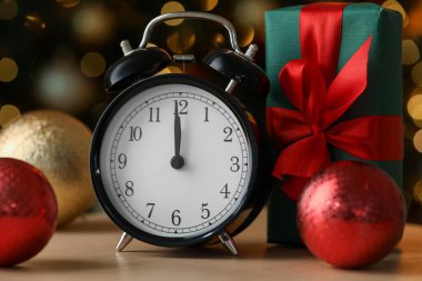 Çalar saat, mücevher ve hediye kutusu ahşap masada bulanık ışıklara karşı, yakın plan. Yeni yıl tebrik kartı.