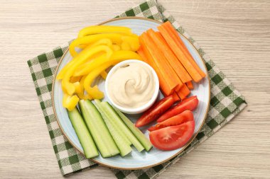 Farklı taze sebzeler ve ahşap masadaki sos.