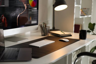 Bilgisayarı, bilgisayarı, bilgisayarı, kupası, kırtasiyesi ve paspası olan şık bir iş yeri.