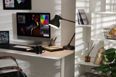 Bilgisayarı, bilgisayarı, bilgisayarı, kupası, kırtasiyesi ve paspası olan şık bir iş yeri.