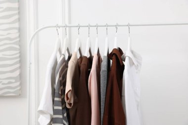 Beyaz duvarın yanında asılı duran farklı kadın kıyafetleri.