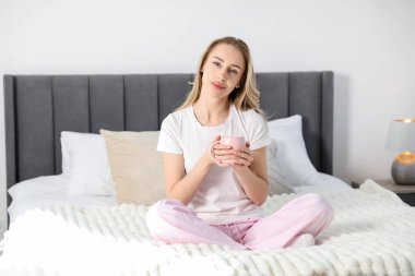 Bir fincan kakaolu kadın evde yatakta içki içiyor.