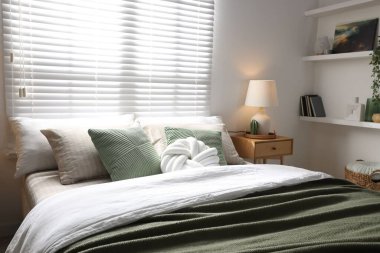 Büyük yataklı, yastıklı, çiçekli ve lambalı şık bir yatak odası. İç tasarım