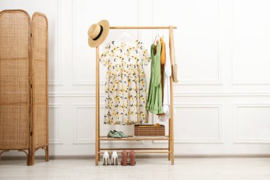 Beyaz duvarın yanında askıda asılı duran farklı kadın kıyafetleri.