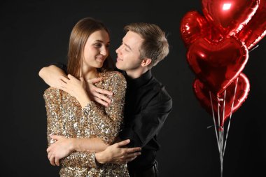 Siyah arka planda kucaklaşan sevimli bir çift. Romantik randevu