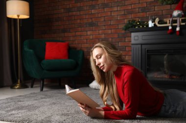 Güzel bir kadın evde yerde kitap okuyor, mesaj için yer var. Noel sezonu