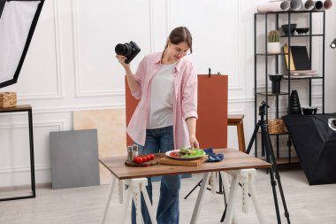 Stüdyoda somon ve sebzelerle kompozisyon hazırlayan bir kadın. Profesyonel yemek fotoğrafçılığı.