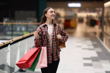 Alışveriş merkezinde farklı çantaları olan bir kadın.