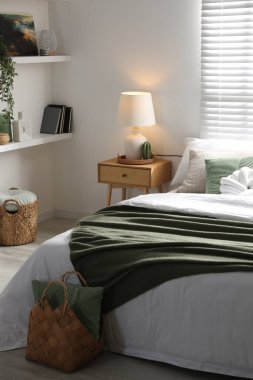 Büyük yataklı, yastıklı, çiçekli ve lambalı şık bir yatak odası. İç tasarım