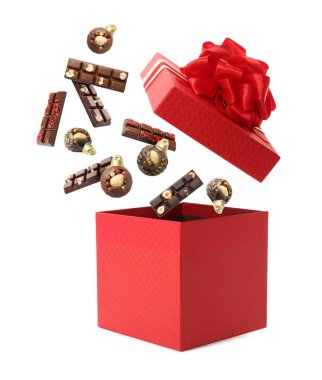 Noel kutlaması. Çikolata şekerleri beyaz arka planda hediye kutusuna düşüyor.