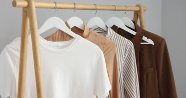 İçerideki ışık duvarının yanında asılı duran farklı şık kıyafetler, yakın plan. Kamera hareket ediyor