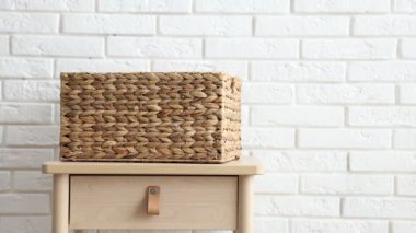 Giysiler çamaşır sepetine düşüyor beyaz tuğla duvarın yanındaki masada, yakın plan.