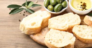 Ciabatta dilimleri, biberli yağ ve ahşap masada zeytin. Kamera sağa hareket ediyor