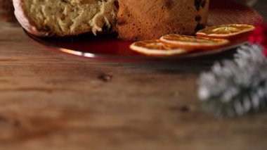 Noel yemeği. Lezzetli Panettone pastası ve ahşap masanın üzerindeki şenlikli dekor. Arka planda bulanık ışıklar, yakın plan. Kamera yukarı hareket ediyor