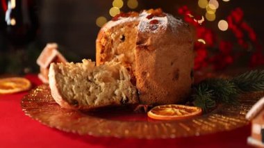 Noel yemeği. Lezzetli Panettone pastası ve arka planda bulanık ışıklarla süslenmiş şenlikli bir dekor, yakın plan. Kamera yukarı hareket ediyor