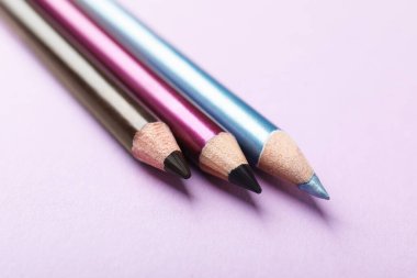 Pembe arka planda renkli göz kalemleri, yakın plan.