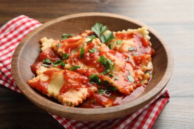 Domates soslu lezzetli ravioli ve ahşap masada maydanoz, yakın plan.