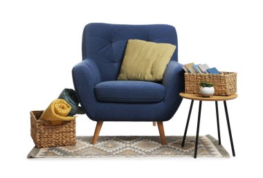 Mavi koltuk, yastık, yan masa, hasır sepetler ve beyaz halı.