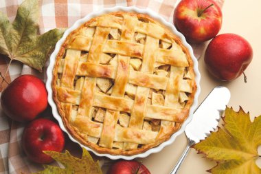 Lezzetli ev yapımı elmalı turta, elmalar, sunucu ve bej arka planda kuru yapraklar, düz uzanma