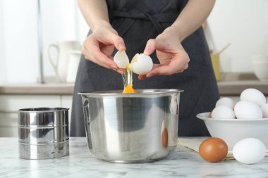 Mutfaktaki beyaz mermer masada yumurta kıran kadın, yakın plan.