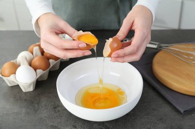 Mutfaktaki gri masada yumurta kıran kadın, yakın plan.