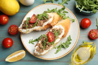 Lezzetli bruschettalar ton balığı, domates, roka, limon ve yağlı açık mavi ahşap masa, düz uzanmış