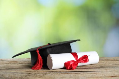 Diploma ve mezuniyet şapkası ahşap masanın üzerinde bulanık arka plan, yakın plan