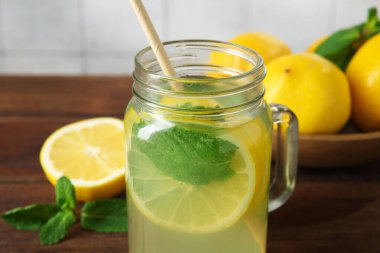 Mason kavanozunda taze limonata, ahşap masada limon ve nane, yakın plan.