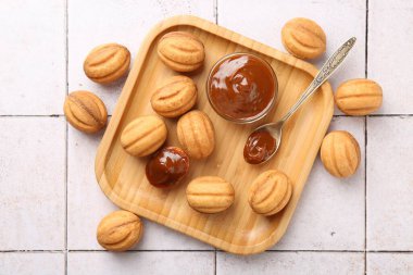 Lezzetli fındık şekilli kurabiyeler, kaynamış konsantre süt, açık fayanslı masa, düz uzanmış.