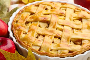 Lezzetli ev yapımı elmalı turta, elmalar ve kuru yapraklar masada, yakın plan.