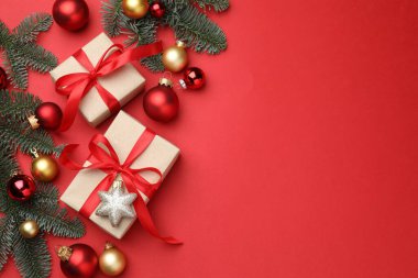 Firavun ağacı dalları, hediyeler ve kırmızı arka planda Noel süsü, düz bir zemin. Metin için boşluk