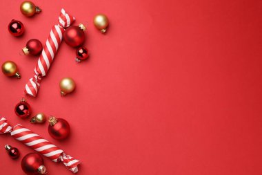 Kırmızı arka planda güzel Noel ağacı süsleri ve şekerler, düz. Metin için boşluk
