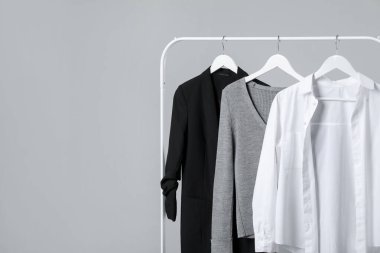 Farklı giysiler gri arka planda asılı, yakın plan. Metin için boşluk