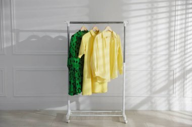 Beyaz duvarın yanındaki askıda asılı farklı şık kıyafetler.